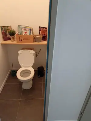 a bathroom with a toilet with a shelf above it at Jolie Maison au centre du village in Gruissan