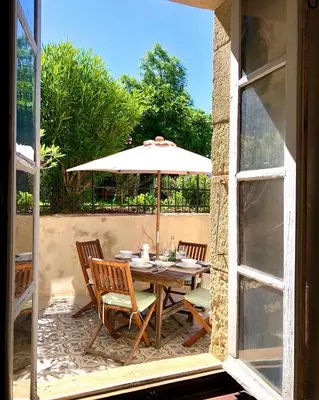 a table and chairs with an umbrella on a patio at Chez Luis et David in Avignonet-de-Lauragais