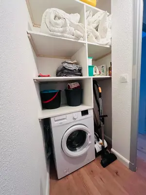 a laundry room with a washer and dryer on shelves at Le Bastide Cosy in Carcassonne