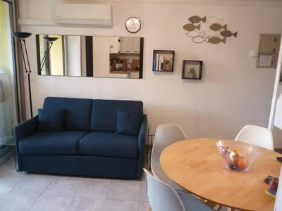 a living room with a blue couch and a table at la playa in Gruissan