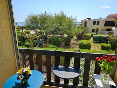 a balcony with a table and chairs and flowers on it at la playa in Gruissan