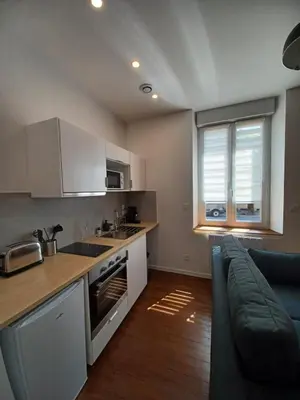 a kitchen with white cabinets and a blue couch at Mazamet - Studio neuf et moderne en centre-ville in Mazamet