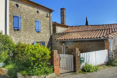 a brick house with a white fence in front of it at La maison bleue in Lautrec