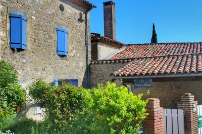an old stone building with blue windows and trees at La maison bleue in Lautrec