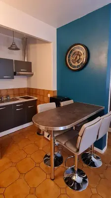 a kitchen with a table and chairs and a clock on the wall at Mazamet : Résidence du Musée centre ville. in Mazamet