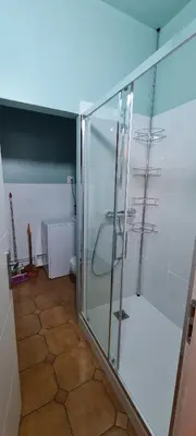 a glass shower in a bathroom with a tiled floor at Mazamet : Résidence du Musée centre ville. in Mazamet