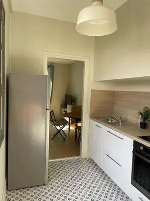 a kitchen with a stainless steel refrigerator and a table at Le Marceau - Maison climatisée avec jardin in Carcassonne
