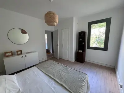 a white bedroom with a bed and a mirror at Le Marceau - Maison climatisée avec jardin in Carcassonne