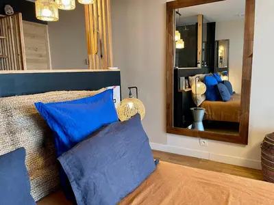 a bedroom with a bed with blue pillows and a mirror at Panorama Suite & Spa in Carcassonne