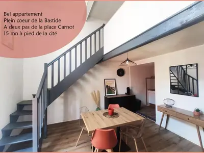 a living room with a table and a staircase at Superbe appartement au cœur du centre ville in Carcassonne