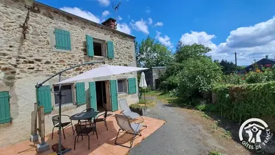 a patio with chairs and an umbrella next to a building at Guyor in Le Bez