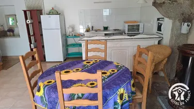 a kitchen with a table and chairs and a refrigerator at Guyor in Le Bez