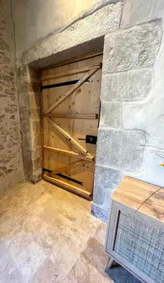 a large wooden garage door in a stone wall at Le Donjon de Lily - Cœur de La Cité Médiévale in Carcassonne