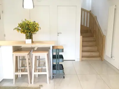 a kitchen with a table and stools and a staircase at Lodge Marie in Villegailhenc