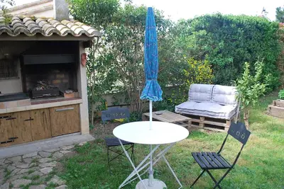 a table and two chairs and an umbrella in a yard at Au Canalet - Le Somail in Le Somail