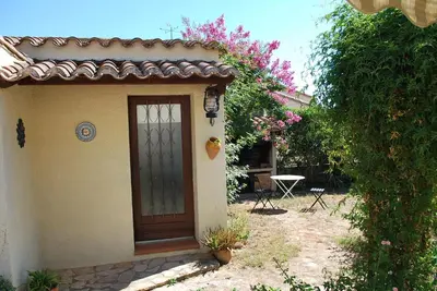 a door of a house with a table and flowers at Au Canalet - Le Somail in Le Somail