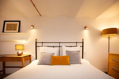 a bedroom with a bed with white sheets and orange pillows at Beautiful converted one bedroom apartment in Carcassonne