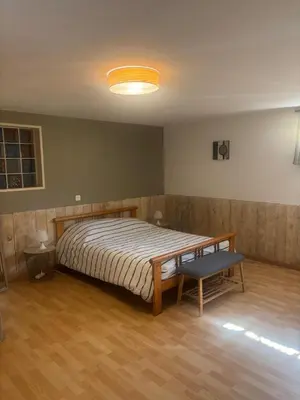 a bedroom with a bed and a bench in it at chez Angélique in Marcorignan