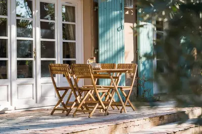 a wooden table and chairs sitting on a porch at Le gite de la closerie des iris in Castelnau-dʼAude