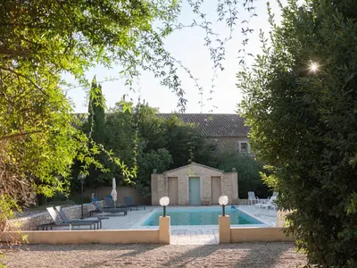 a swimming pool in a yard with trees and a building at Le gite de la closerie des iris in Castelnau-dʼAude