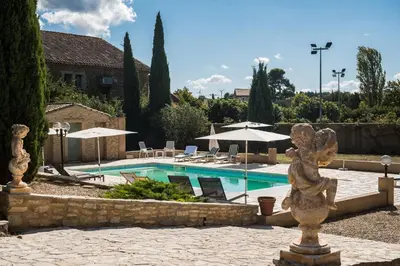 a swimming pool with a statue in front of a building at Le gite de la closerie des iris in Castelnau-dʼAude