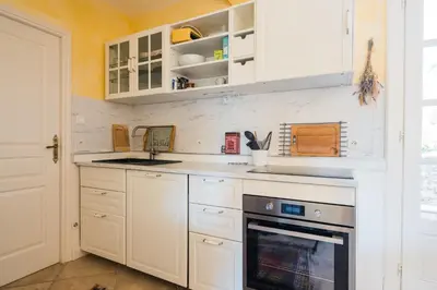 a kitchen with white cabinets and a sink and a stove at Le gite de la closerie des iris in Castelnau-dʼAude