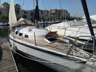 a white boat docked in a marina with other boats at St Helene in Gruissan