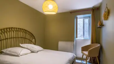 a bedroom with a bed and a chair and a window at Belle et grande maison de village au bord de l'eau in Peyriac-de-Mer