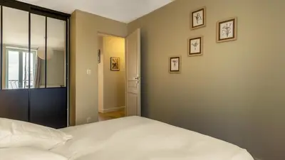 a bedroom with a white bed and some pictures on the wall at Belle et grande maison de village au bord de l'eau in Peyriac-de-Mer