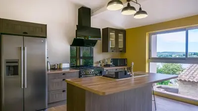 a kitchen with yellow walls and a stainless steel refrigerator at Belle et grande maison de village au bord de l'eau in Peyriac-de-Mer