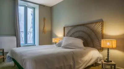 a bedroom with a large white bed with two lamps at Belle et grande maison de village au bord de l'eau in Peyriac-de-Mer