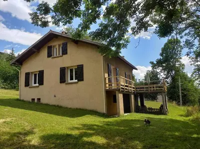 a house with a dog standing in front of it at Belle maison proche de la ville et du lac in Belcaire