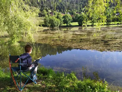a boy sitting in a chair looking at a lake at Belle maison proche de la ville et du lac in Belcaire