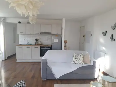 a living room with a white couch and a kitchen at les jardins de l'archevêché in Narbonne