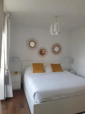 a bedroom with a white bed with two mirrors on the wall at les jardins de l'archevêché in Narbonne