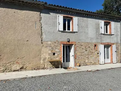 a stone building with two windows and a door at L’oustal in Vaudreuille