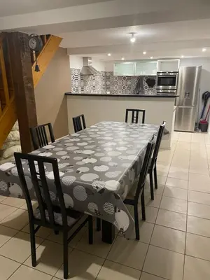 a dining room table with chairs and a kitchen at L’oustal in Vaudreuille