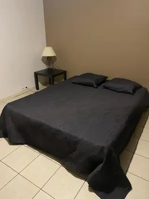 a bed in a bedroom with a black comforter at L’oustal in Vaudreuille