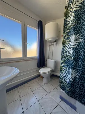 a bathroom with a toilet and a sink and a window at Le Lamourguier in Narbonne