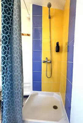 a bathroom with a shower with a blue and yellow tiles at Le Lamourguier in Narbonne