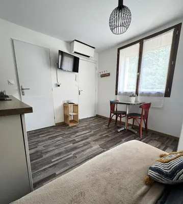 a living room with a table and a kitchen at Le Lamourguier in Narbonne