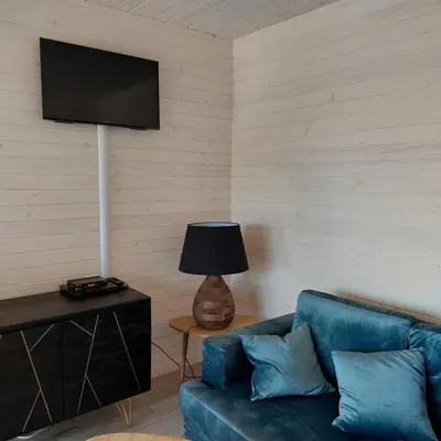 a living room with a blue couch and a flat screen tv at Lodge d'Œnotourisme avec vue imprenable ! in Vingrau