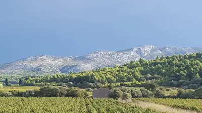 an old barn in a field with mountains in the background at Gîte dans ancienne bergerie en pleine garrigue in Fraissé-des-Corbières