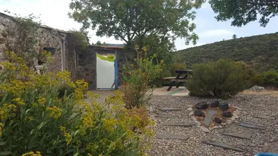 a garden with a bench and a table in the background at Gîte dans ancienne bergerie en pleine garrigue in Fraissé-des-Corbières