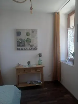 a bedroom with a bed and a table and a window at Chambre d'hôte Au Jardin Le clos des vins d'Anges in Saint-Pierre-des-Champs