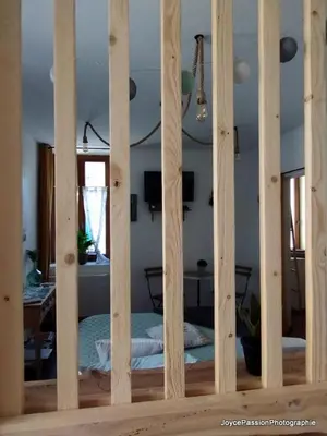 a bedroom with a bed through a wooden frame at Chambre d'hôte Au Jardin Le clos des vins d'Anges in Saint-Pierre-des-Champs