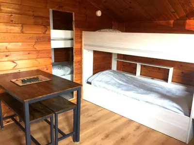 a bedroom with a bunk bed and a table at Chalet en bois 
