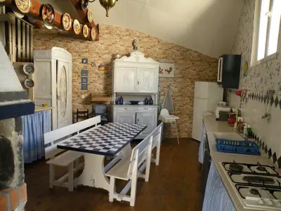a kitchen with white cabinets and a table with chairs at GRANDE MAISON FAMILIALE in Escouloubre
