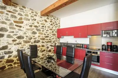 a kitchen with red cabinets and a stone wall at Côté Vignes à Bélesta in Bélesta