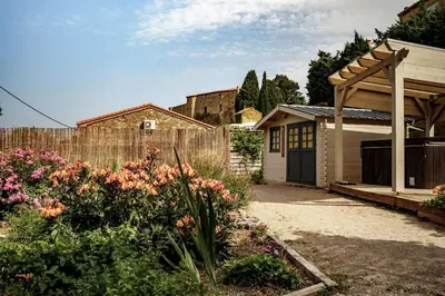 a house with a fence and a garden with flowers at Côté Vignes à Bélesta in Bélesta